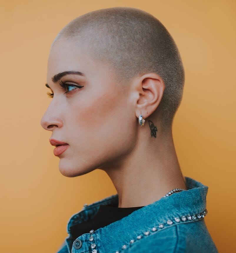 a close up of a woman with a shaved head and piercings