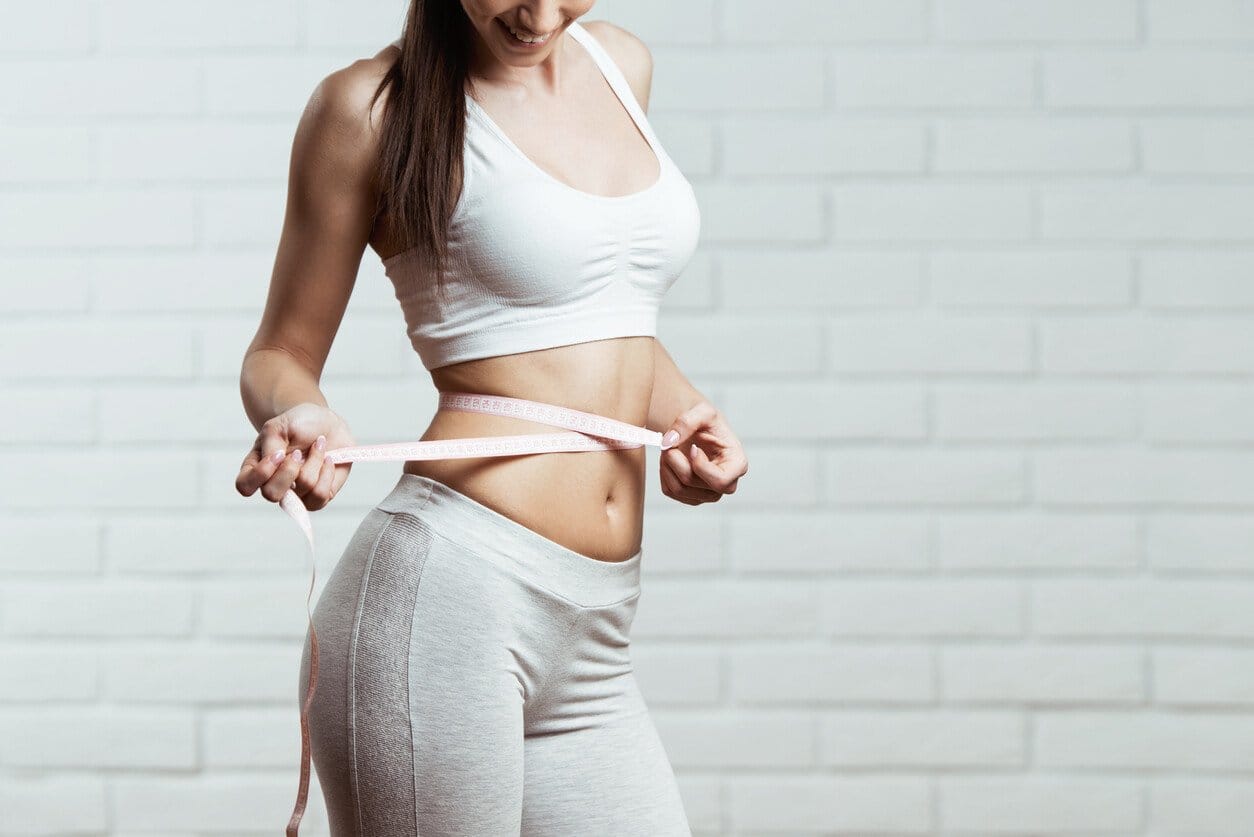 Woman measuring waist with measuring tape