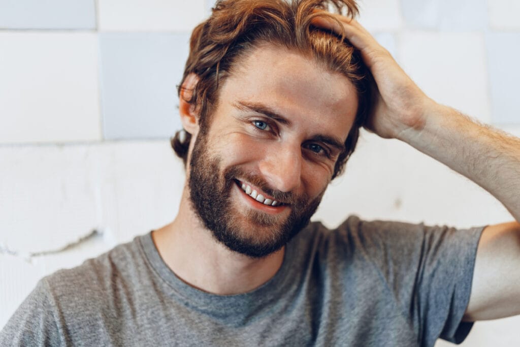 Man running hand through thick hair after non-surgical hair restoration