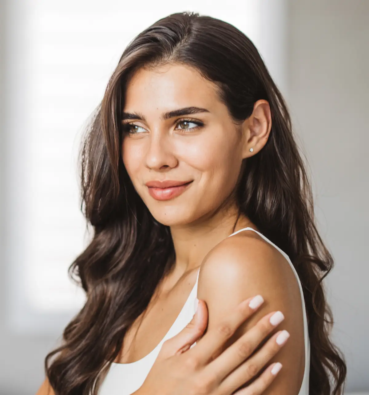 Portrait of woman smiling with wavy brown hair, looking away from camera